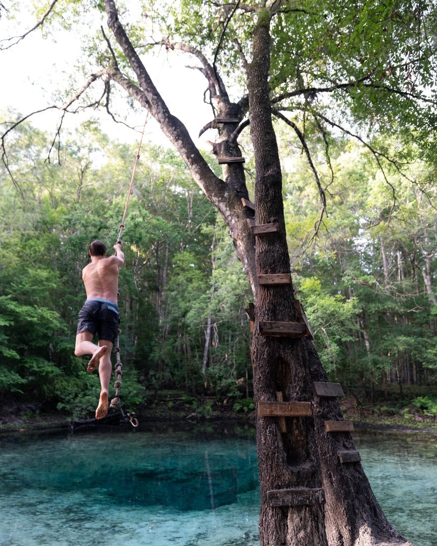 Brandon on a rope swing over a clear Florida spring